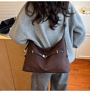 Detail of dark brown matte hobo bag with leather straps and metal hardware accents