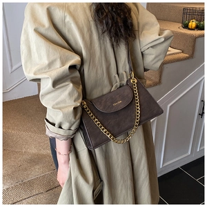 Gros plan d'un sac à bandoulière rétro marron foncé avec chaîne dorée sur un mannequin