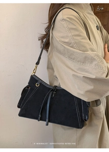 Detailansicht der schwarzen Wildleder-Tasche mit weißen Kontrastnähten und Vintage-Beschlägen