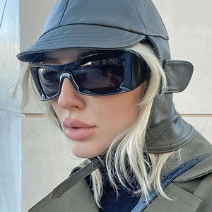 Close-up of black retro chunky frame sunglasses with a leather aviator cap on model