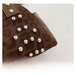 Macro shot of leopard print faux suede fabric with silver metal studs on a shoulder bag