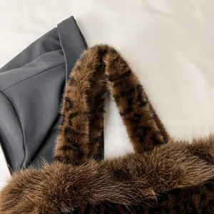 Detail of soft brown faux fur handbag with leopard print handle texture and plush finish