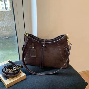 Macro detail of retro brown suede bag with white contrast stitching and gold hardware