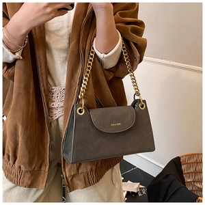 Gros plan d'un sac à bandoulière en cuir vintage avec chaîne dorée et logo en métal