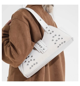 Detail of white leather shoulder bag with silver rivet studs on textured surface