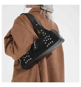 Detail of black rivet shoulder bag with leopard texture and silver studs on brown coat