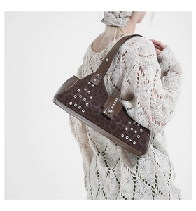 Close-up of leopard print shoulder bag with silver rivets on model in white sweater