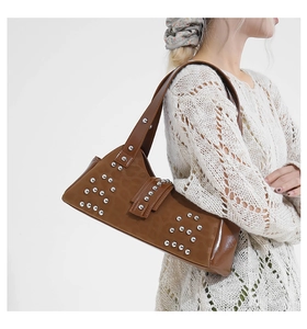 Detail of a brown leather shoulder bag with dense silver rivet studs and a wide strap