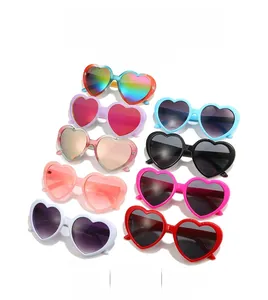Flat lay of heart-shaped sunglasses in ten diverse colors including rainbow and pink
