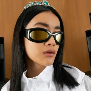 Nahaufnahme der futuristischen Wrap-Around-Sonnenbrille mit schwarzem Rahmen und Goldgläsern