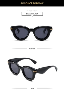 Detail view of black oval chunky sunglasses with gold metal accents on temples