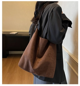 Detail of the large brown suede tote bag worn on shoulder in a vintage room setting