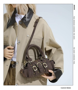 Close-up of dark brown suede handbag with golden buckles and adjustable strap details