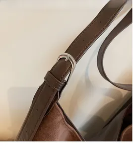Macro shot of brown suede tote bag strap with silver metal buckle and adjustable holes