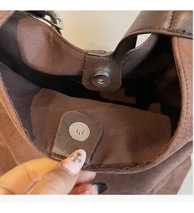 Close-up of silver magnetic clasp and serial number on brown suede tote bag