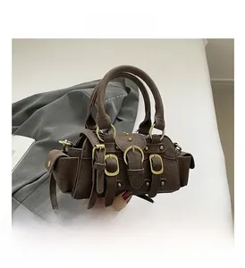 Macro detail of brown suede motorcycle bag with vintage buckles and metal rivets