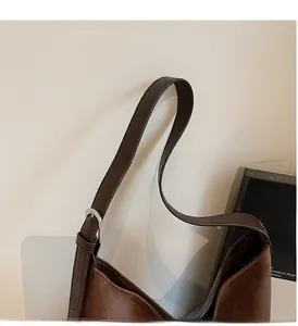 Detail of dark brown suede tote featuring adjustable leather shoulder strap and silver buckle