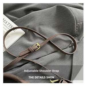 Detail of adjustable brown leather shoulder strap with golden buckle and stitching