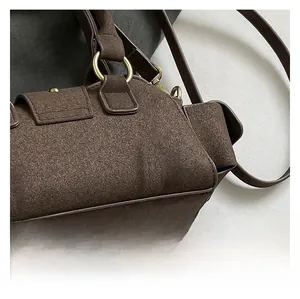 Detailed macro view of dark brown suede handbag with golden metal ring and magnetic flap