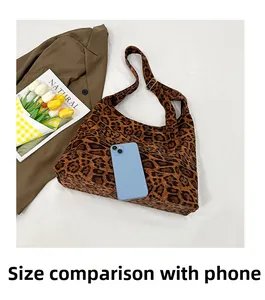 Comparaison de taille entre le cabas en toile léopard et un smartphone sur fond blanc