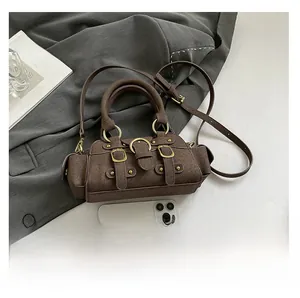 Mini brown suede bag detail with gold buckles shown next to a smartphone for scale