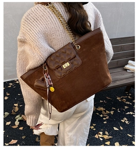 Detail of brown suede tote bag with quilted front pocket and gold chain strap