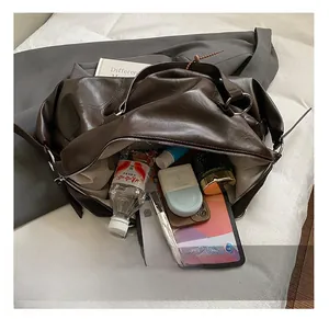 Dettaglio dell'ampio interno della borsa tote in pelle PU marrone con fodera e oggetti