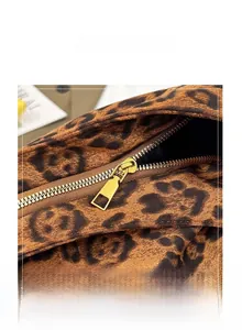 Détail d'une fermeture éclair dorée et d'un tissu imprimé léopard sur un sac fourre-tout