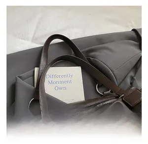 Dettaglio della borsa tote in pelle marrone scuro con finiture argentate e orsetto