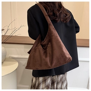 Sac hobo en daim marron porté par un mannequin pour un look minimaliste chic