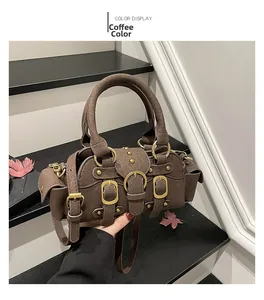 Dettaglio borsa a mano in pelle scamosciata marrone con fibbie e borchie dorate