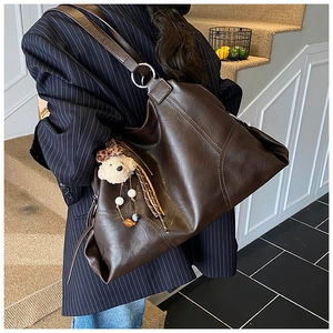 Détail du grand cabas en cuir marron foncé avec anneaux et breloque ours en peluche