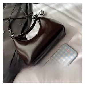 Detailed view of dark brown glossy leather underarm bag with silver zipper and sphere charm
