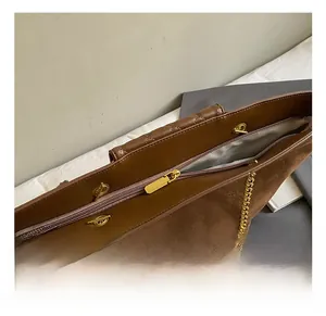 Detail of dark brown tote bag showing gold chain strap and zipper on suede leather