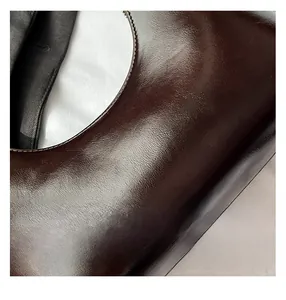 Close-up of high-quality dark brown waxed leather with precise stitching details