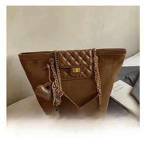Detail of brown suede tote bag with metal turn-lock closure and gold chain strap
