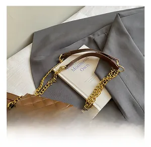 Detail of brown tote bag with suede texture, quilted pocket, and gold chain strap
