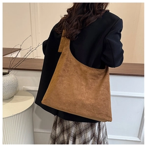 Détail d'un grand sac bandoulière en daim marron montrant la texture douce et la sangle