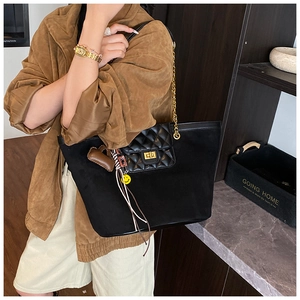 Detail of black matte tote bag with gold chain strap and heart charm decoration