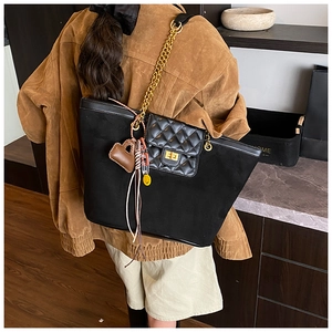 Detail of black suede tote bag with diamond quilted leather flap and gold chain strap