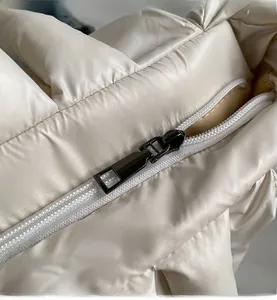 Detail shot of the smooth metal zipper and quilted puffer fabric on the off-white tote bag