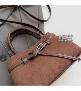 Detail of soft dark brown suede handbag with circular handle and elegant leather strap