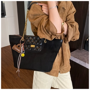Detail of black large tote bag featuring quilted flap, gold twist lock and bag charms