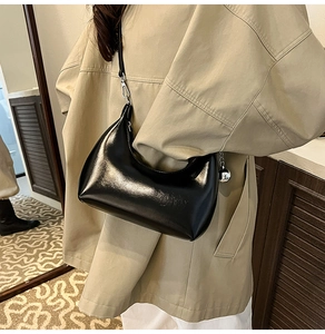 Close-up of black glossy patent leather shoulder bag with silver metallic ball charm detail