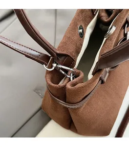Detail of brown suede bucket bag featuring premium leather handles and silver hardware