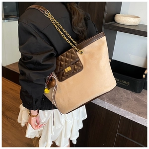 Detail of a large beige tote bag with a brown quilted pocket and gold chain strap