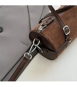 Close-up of premium silver hardware and brown suede texture on the cylinder bag