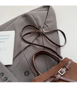 Detail of brown matte suede bucket bag showing adjustable shoulder strap on blazer