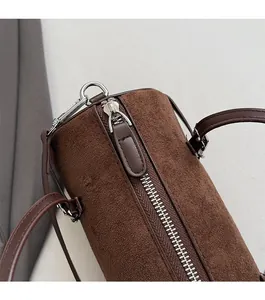 Detailed close-up of dark brown suede bowling bag featuring silver zipper and leather texture