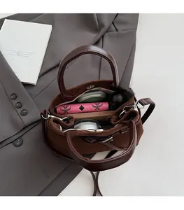 Top view of spacious brown suede bucket bag with wallet, lipstick and phone inside